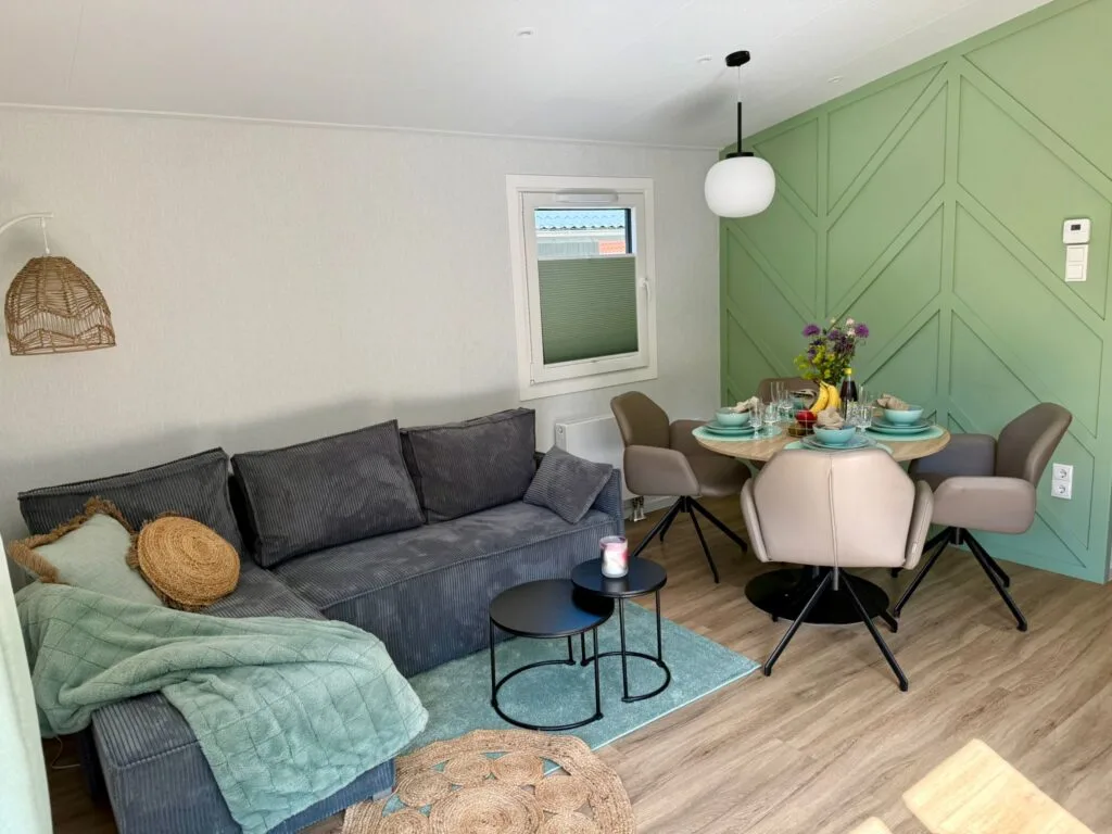 Wohnbereich mit Sofa, Esstisch und grüner Wand