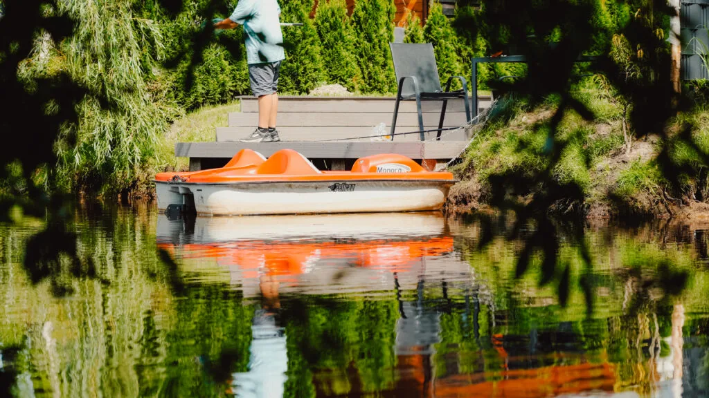 Oranges Tretboot liegt am Steg am Moorsee
