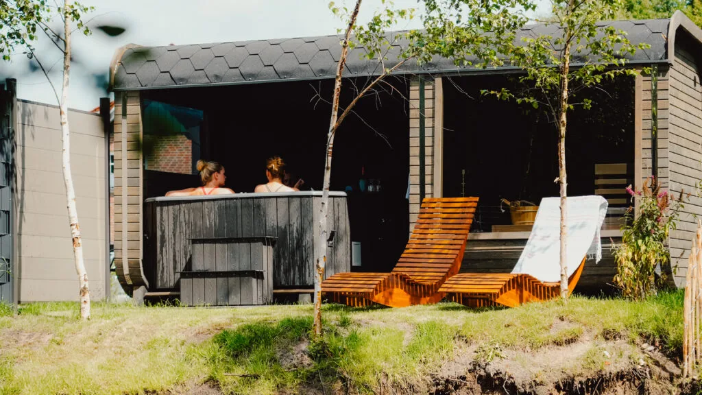 Gäste im Hot Tub vor dem Spa-Cube mit Holzliegen