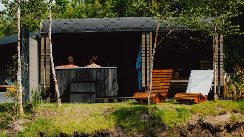 Spa-Cube mit Sauna und Hot Tub, davor Holzliegen im Garten