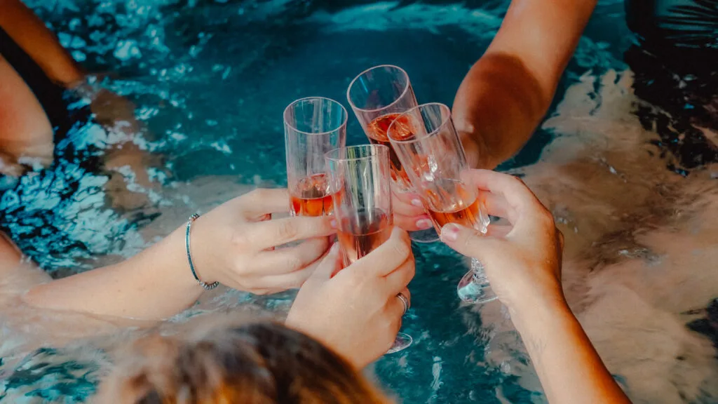 Gäste stoßen mit Gläsern im Hot Tub an