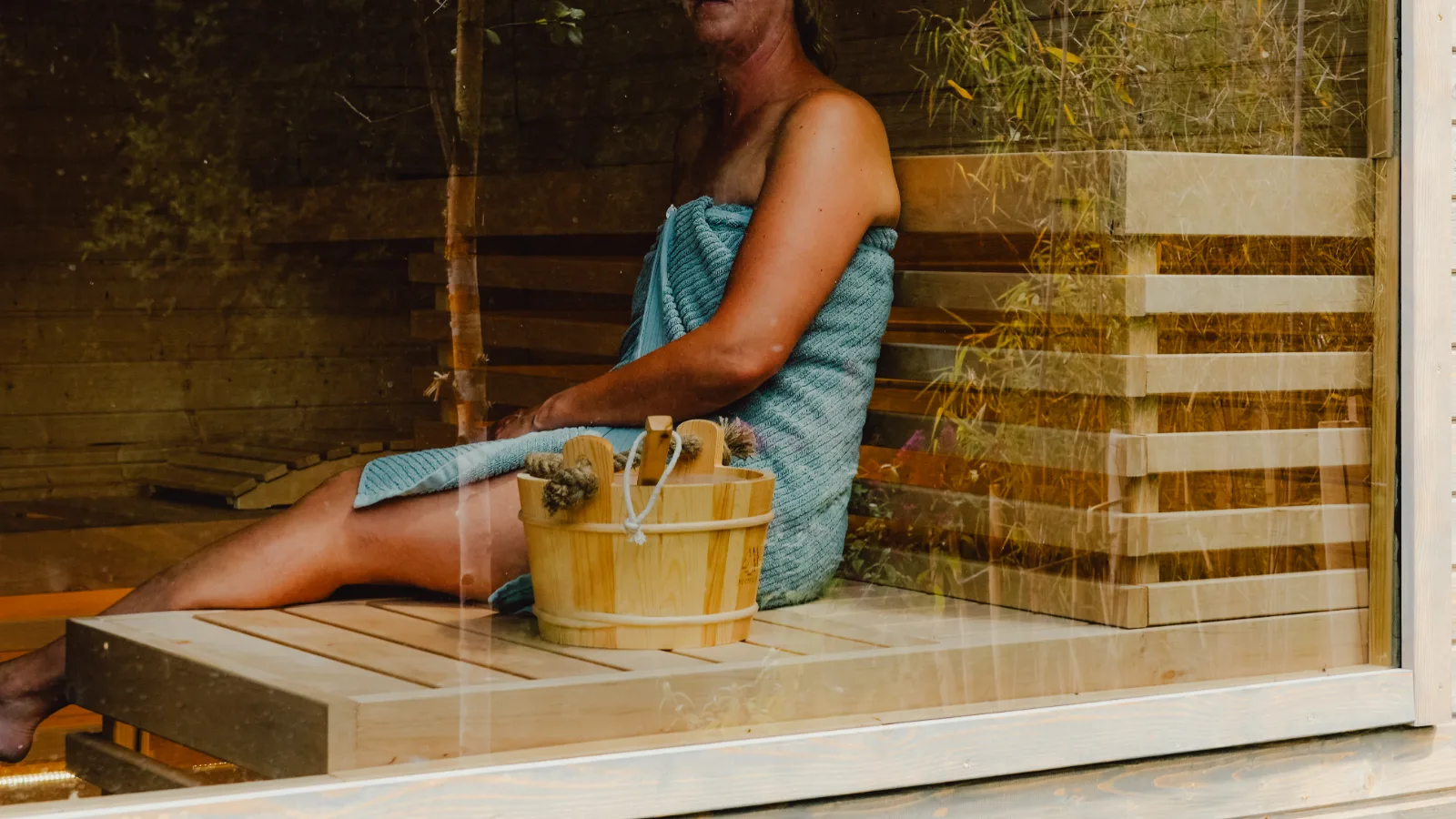 Frau entspannt mit Handtuch in der Sauna