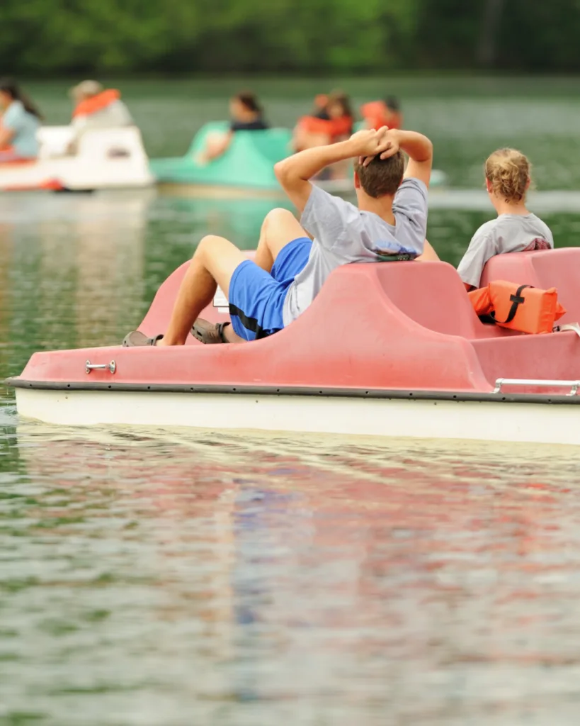 Kinder fahren im roten Tretboot auf dem See